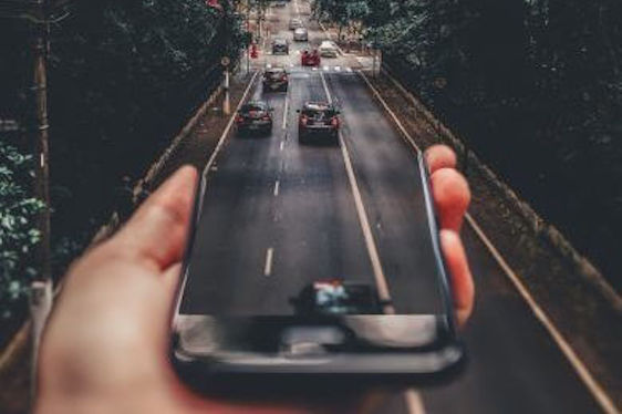 A person taking a picture of a car on a cell phone.