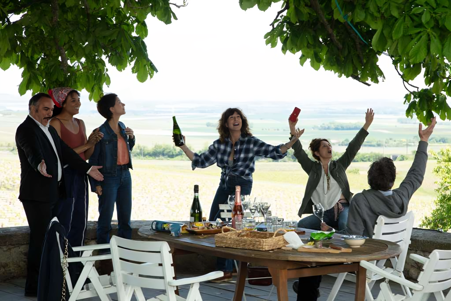 A group of people sitting on a patio with their cars.